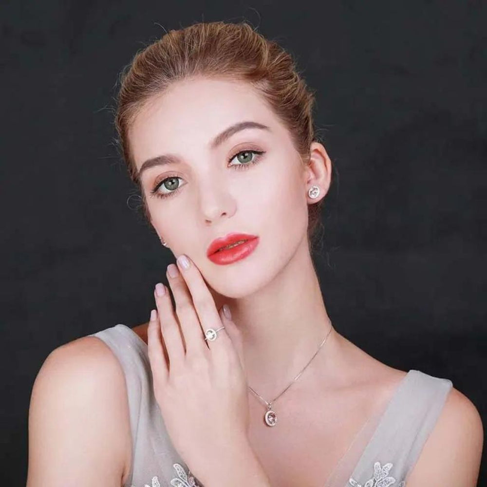 Model showcasing oval pink sapphire halo stud earrings in 18K white gold, with a delicate necklace and elegant makeup.