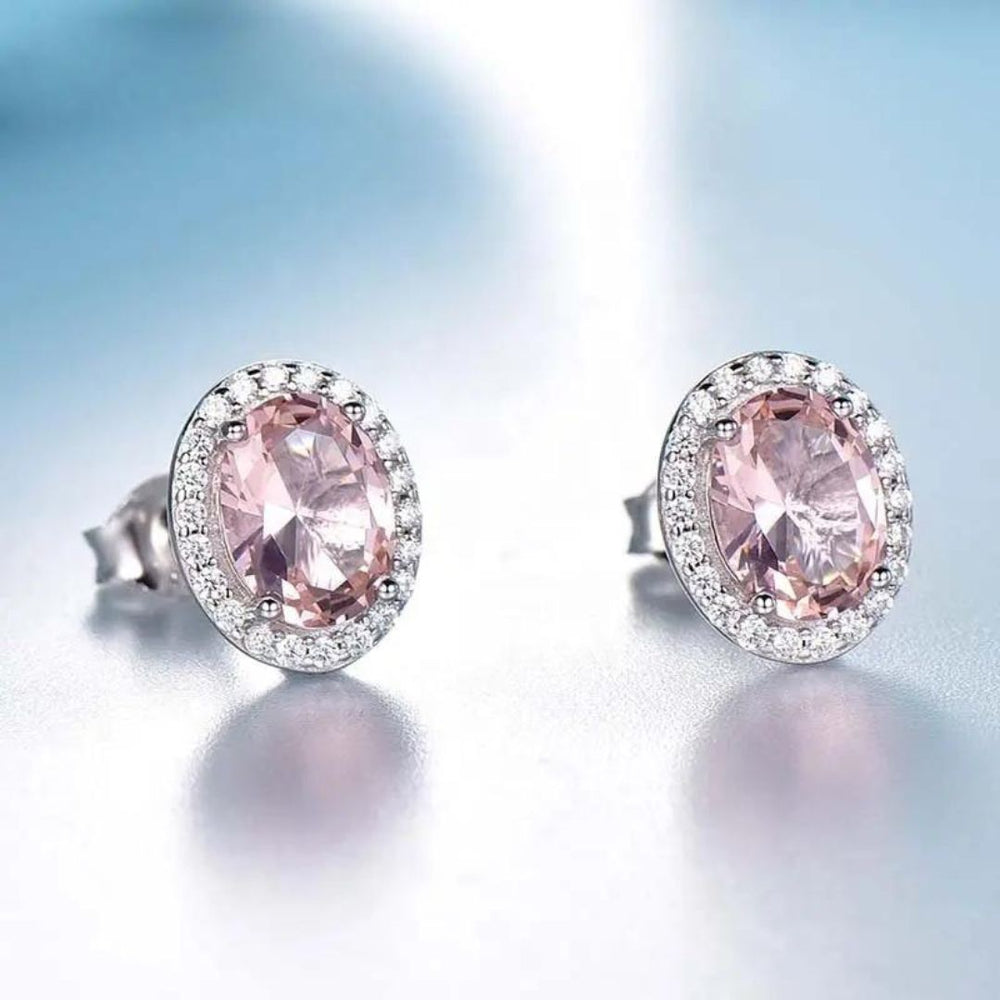 Oval Pink Sapphire Halo Stud Earrings set in 18K white gold with sparkling diamonds, showcasing vibrant pink sapphires.