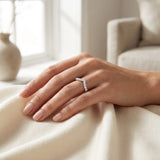 Hand wearing a diamond ring on a soft, neutral background