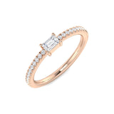Rose gold ring with emerald-cut diamond and smaller diamonds on a white background