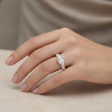 Silver ring with a marquise-shaped diamond on a hand against a neutral background