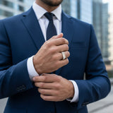 Man in a blue suit adjusting his jacket with a blurred cityscape background