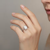 Hand wearing a diamond ring against a neutral background