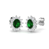 Halo stud earrings with oval emerald prong setting and cluster prong set diamonds