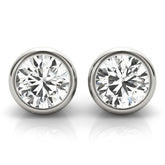 Close-up of bezel-set round lab-grown diamond stud earrings in yellow gold with push-back closures.