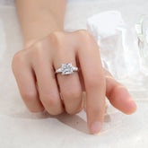 Silver ring with a diamond on a finger against a white background