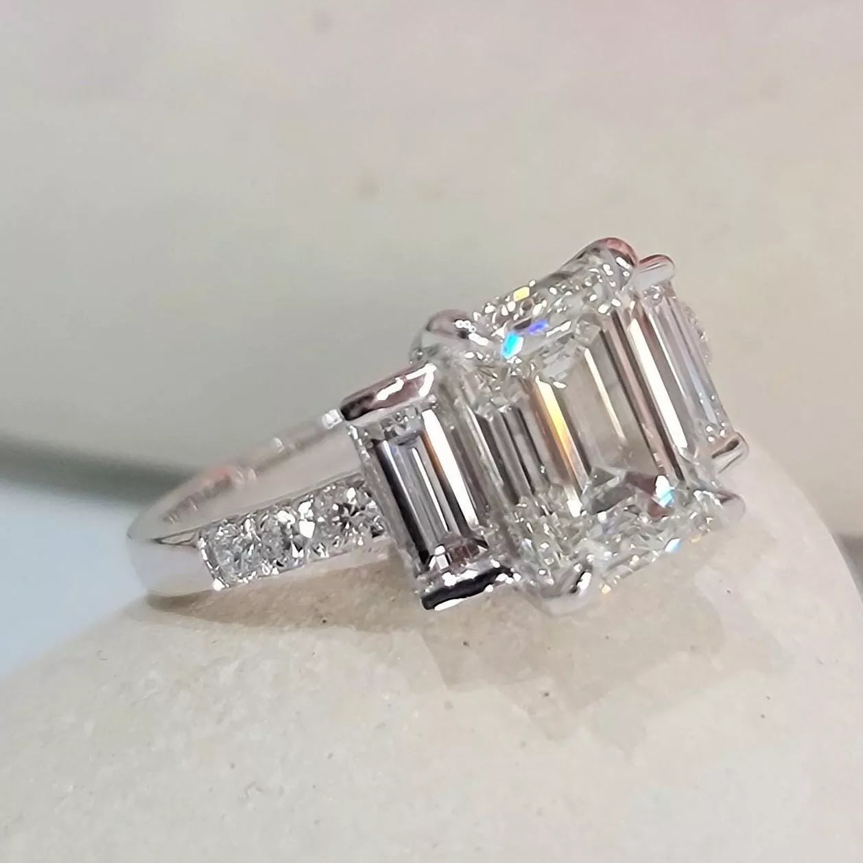Diamond ring with emerald-cut stones on a light background