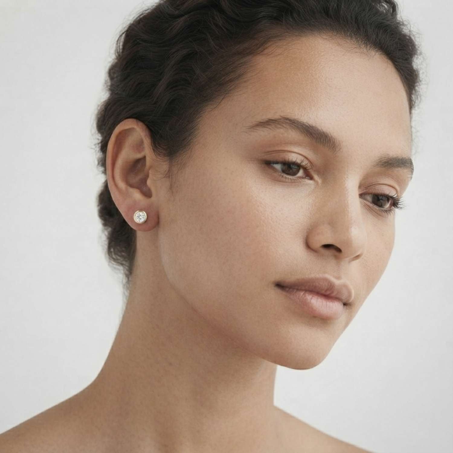 Premium 18K white gold bezel-set solitaire diamond studs reflecting natural light.