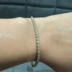 Silver bracelet with clear stones on a wrist against a blue textured background