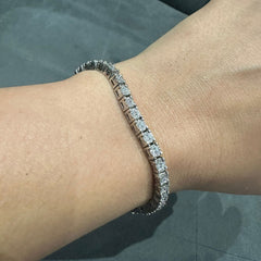 Silver bracelet with clear stones on a wrist against a neutral background