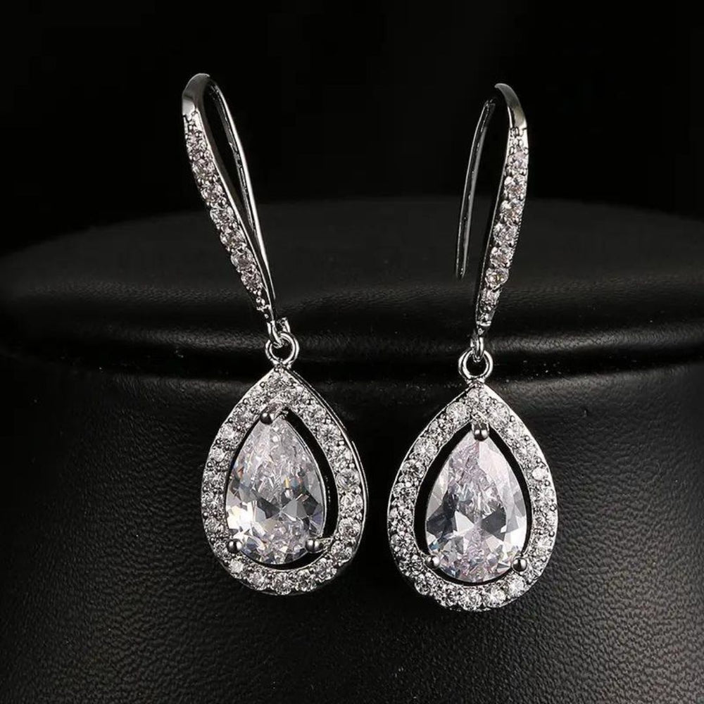 A pair of silver drop earrings with pear-shaped lab-grown diamonds in a pave setting.