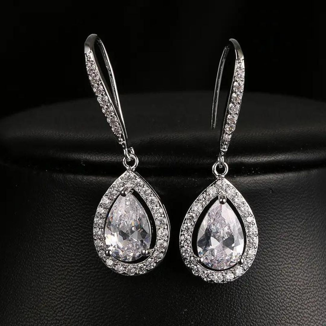 A pair of silver drop earrings with pear-shaped lab-grown diamonds in a pave setting.