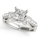 Diamond ring with a central princess-cut diamond and smaller round diamonds on a white background