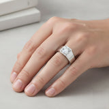 Hand wearing a silver ring with a diamond on a light background