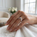 Hand wearing a diamond ring with a blurred indoor background