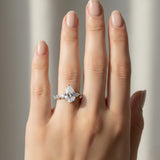 Hand wearing a diamond ring with a neutral background