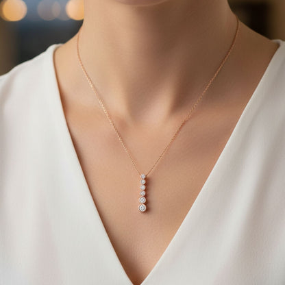Delicate necklace with a pendant on a person wearing a white top.