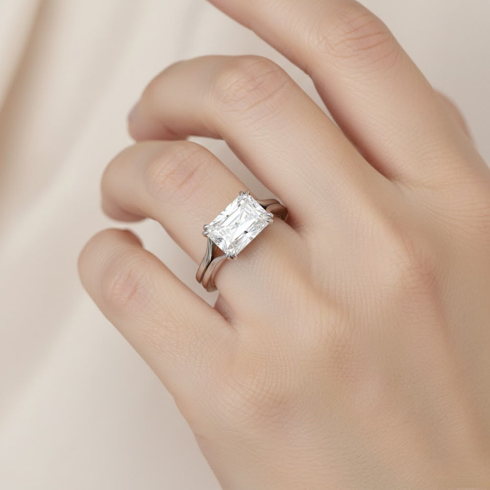 Diamond ring on a finger against a neutral background
