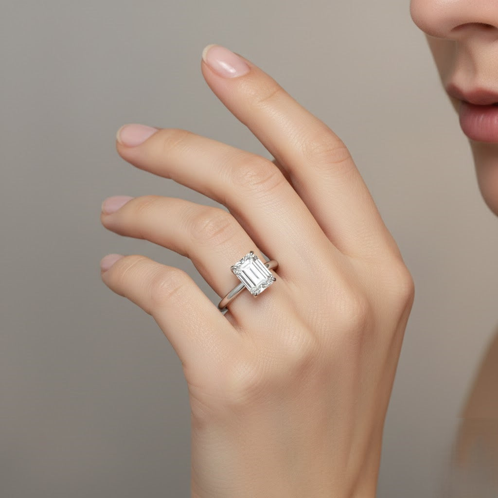Hand wearing a diamond ring against a neutral background