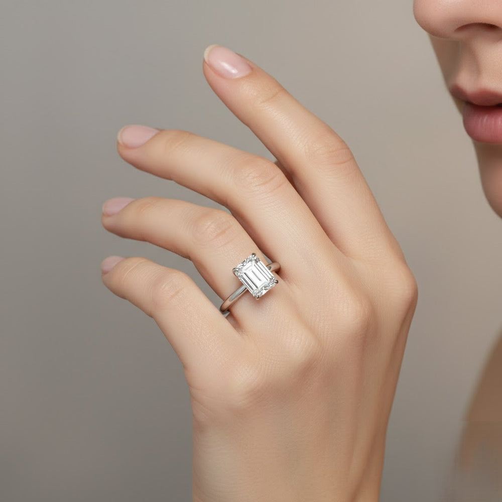 Hand wearing a diamond ring against a neutral background