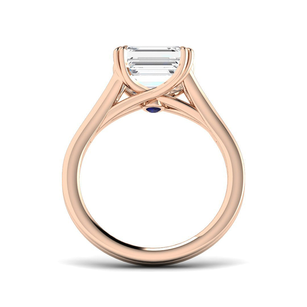 Rose gold ring with a large diamond and blue gemstone on a white background