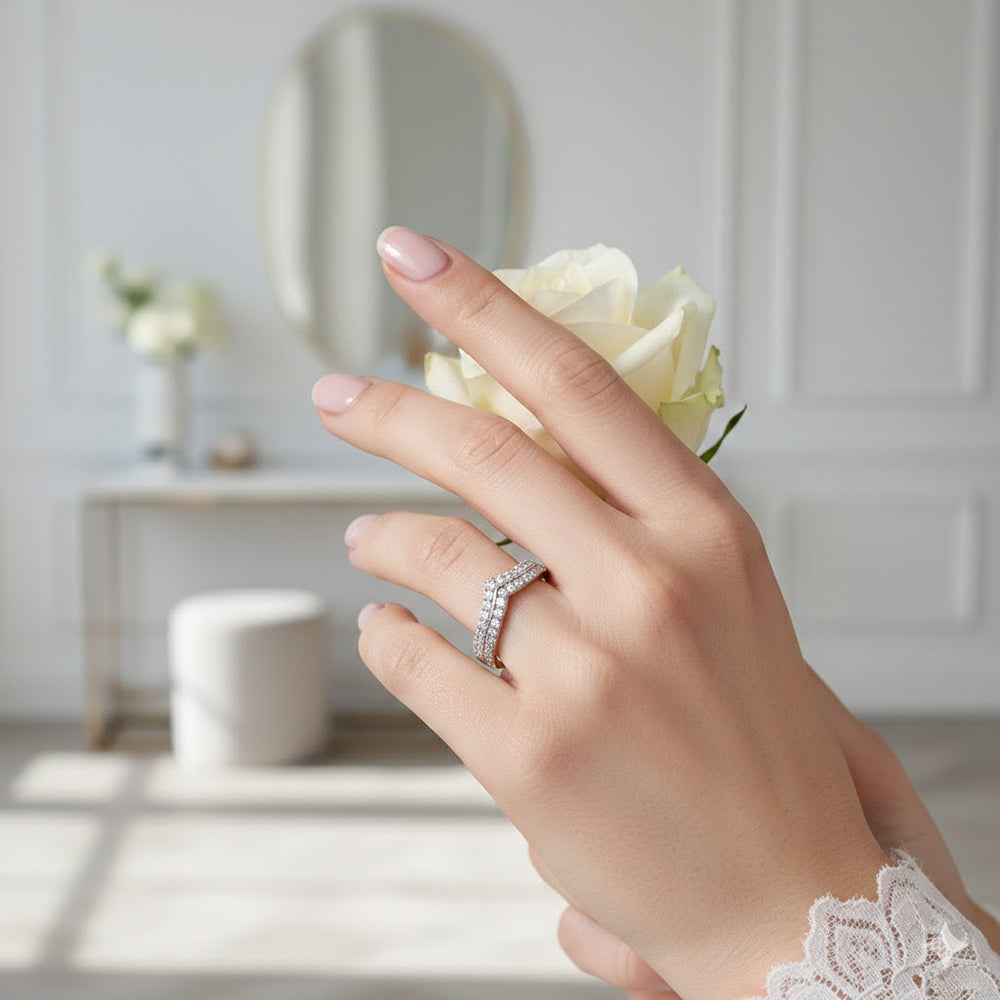 Hand wearing a ring with a white rose, blurred indoor background