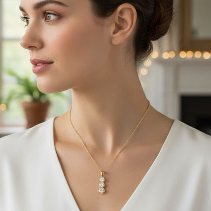 Woman wearing a gold necklace with a pendant indoors
