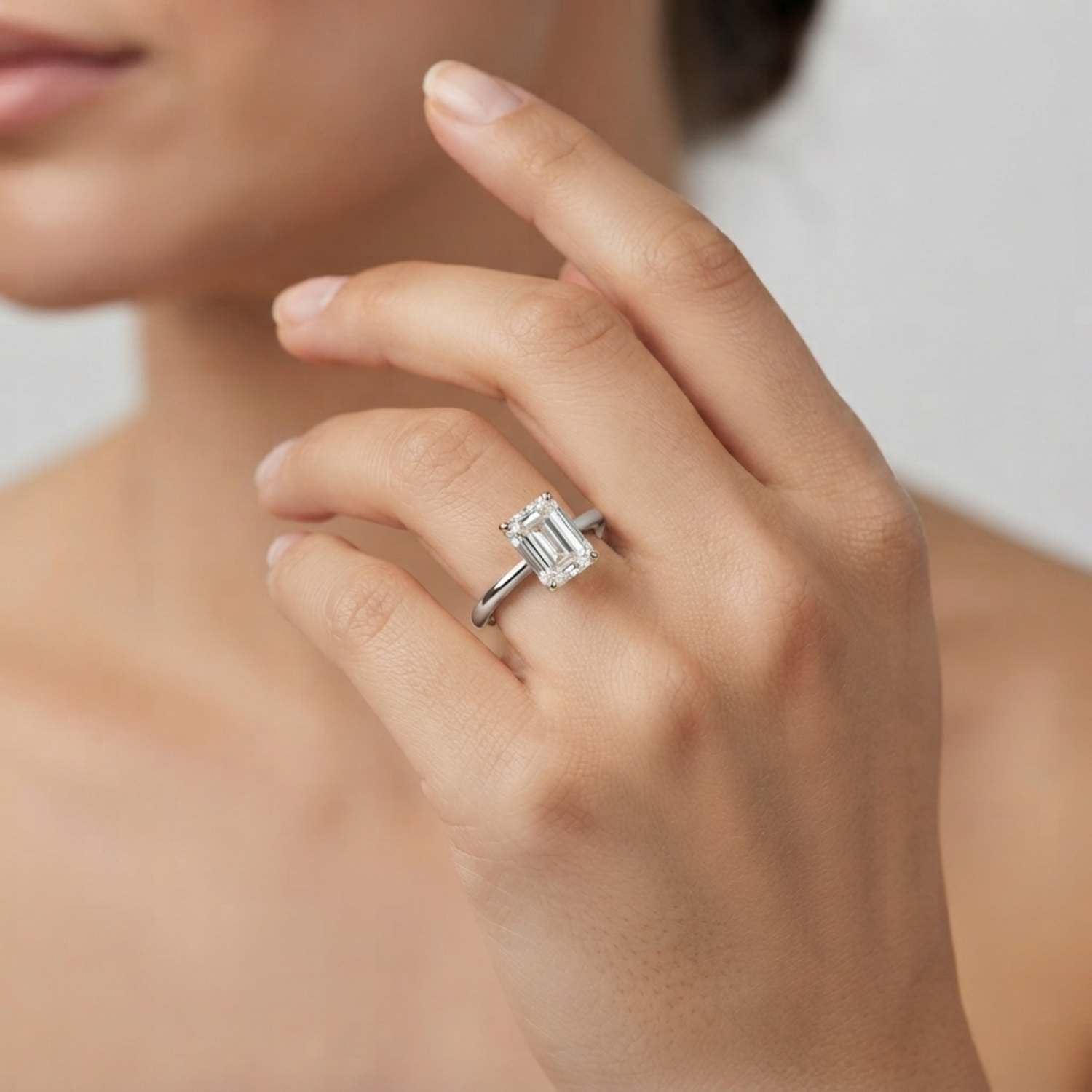 Close-up of a D color VVS clarity emerald-cut lab diamond solitaire ring featuring a classic 4-prong setting.