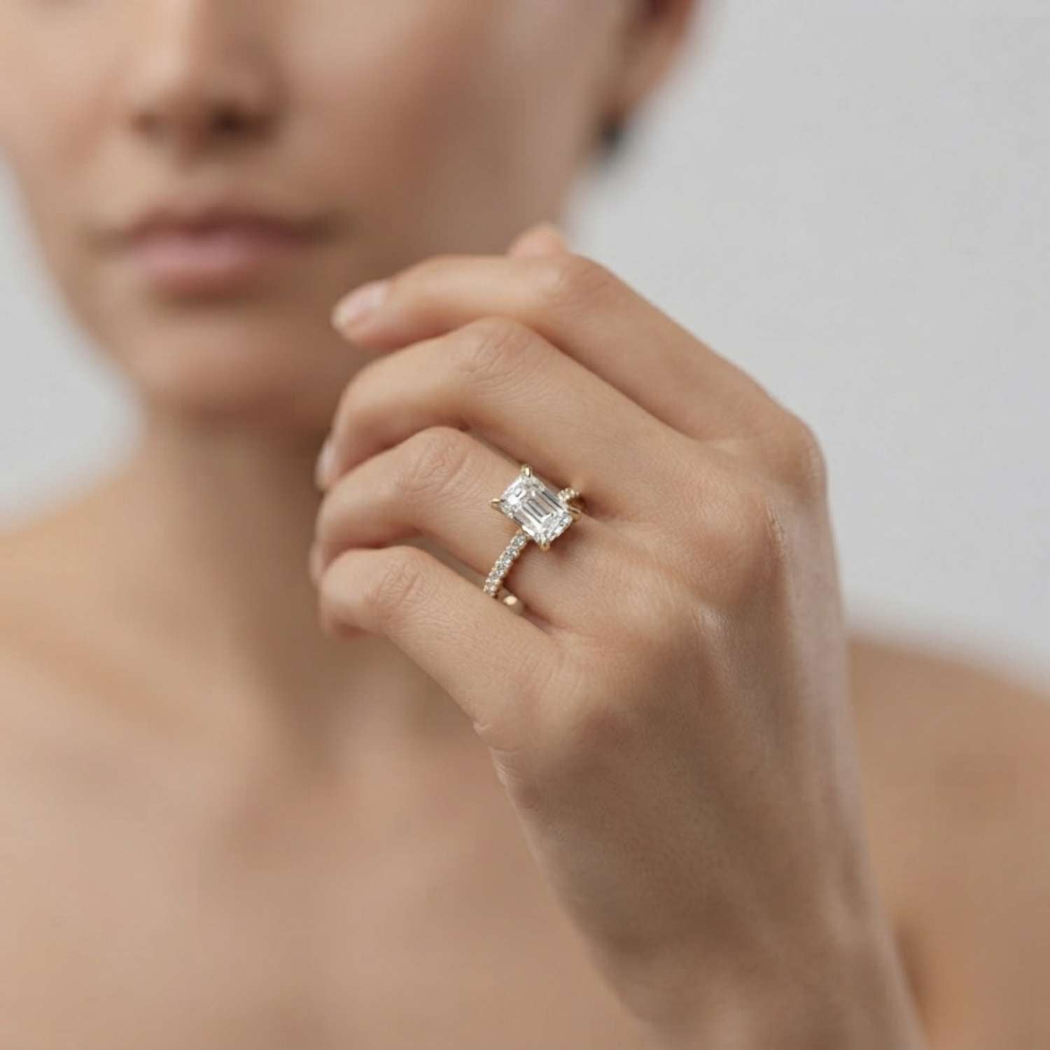 Angled view of an emerald-cut lab diamond ring highlighting its step-cut facets and side diamond band.