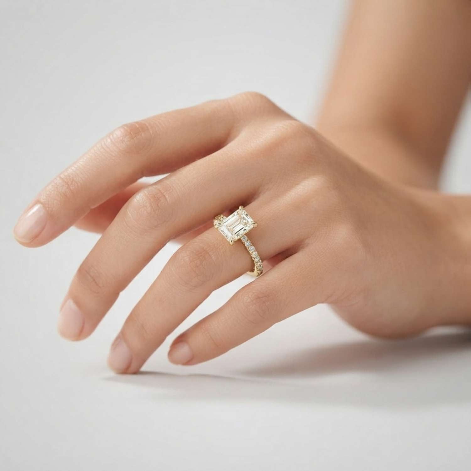 Close-up of an emerald-cut lab diamond ring with a sparkling micro-pave diamond band in white gold.