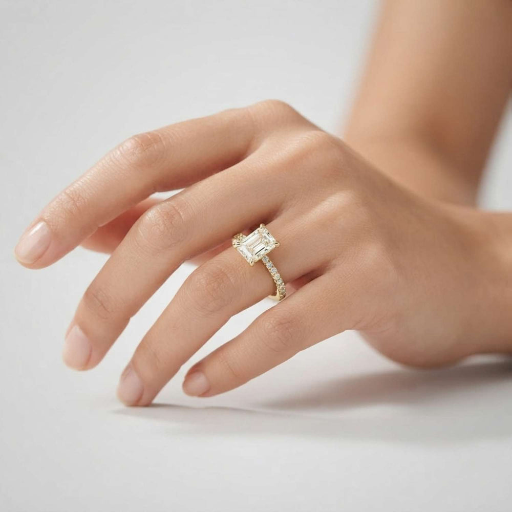 Close-up of an emerald-cut lab diamond ring with a sparkling micro-pave diamond band in white gold.