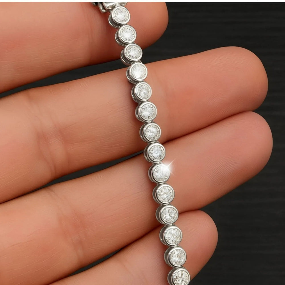 Close-up of round diamonds in individual bezel settings along a white metal tennis bracelet.