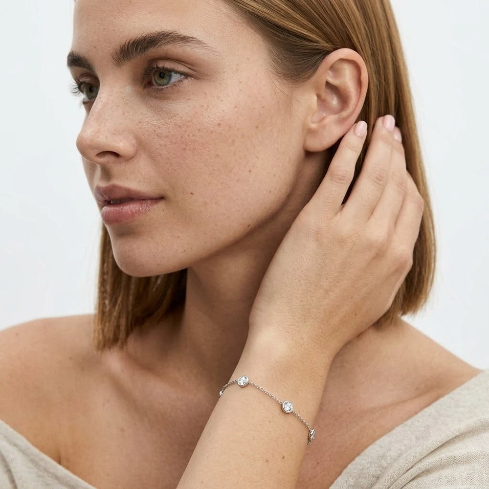 FineDiam delicate diamond chain bracelet with round bezel settings connected by a slim white metal chain.