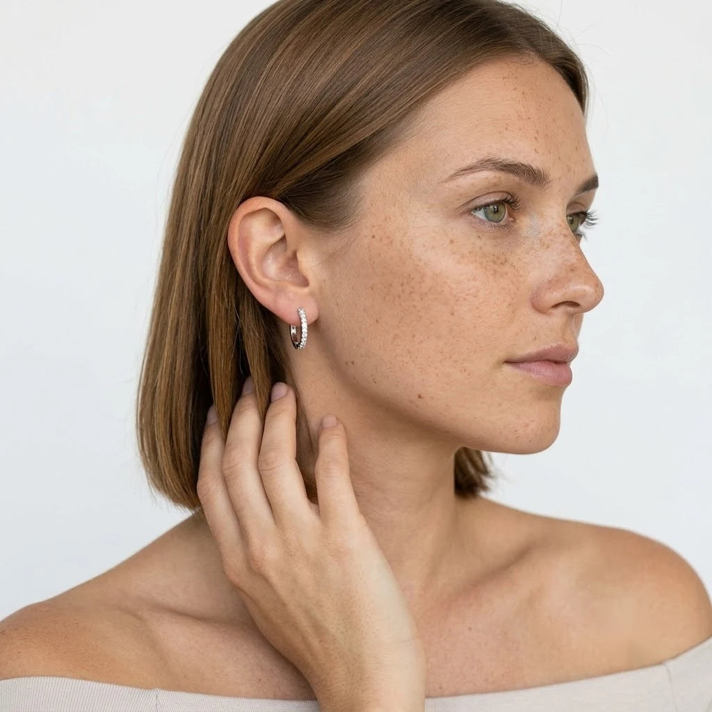 FineDiam white metal diamond hoop earrings with small round stones along the outer curved surface.