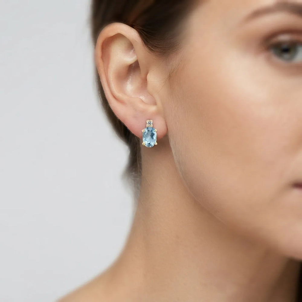 Oval pale blue gemstone and diamond accent earring in yellow gold, side view.