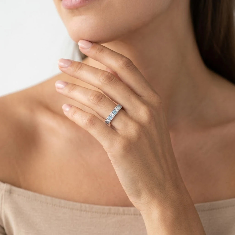 Blue gemstone and diamond band ring with polished metal edges and round stone accents, angled view.