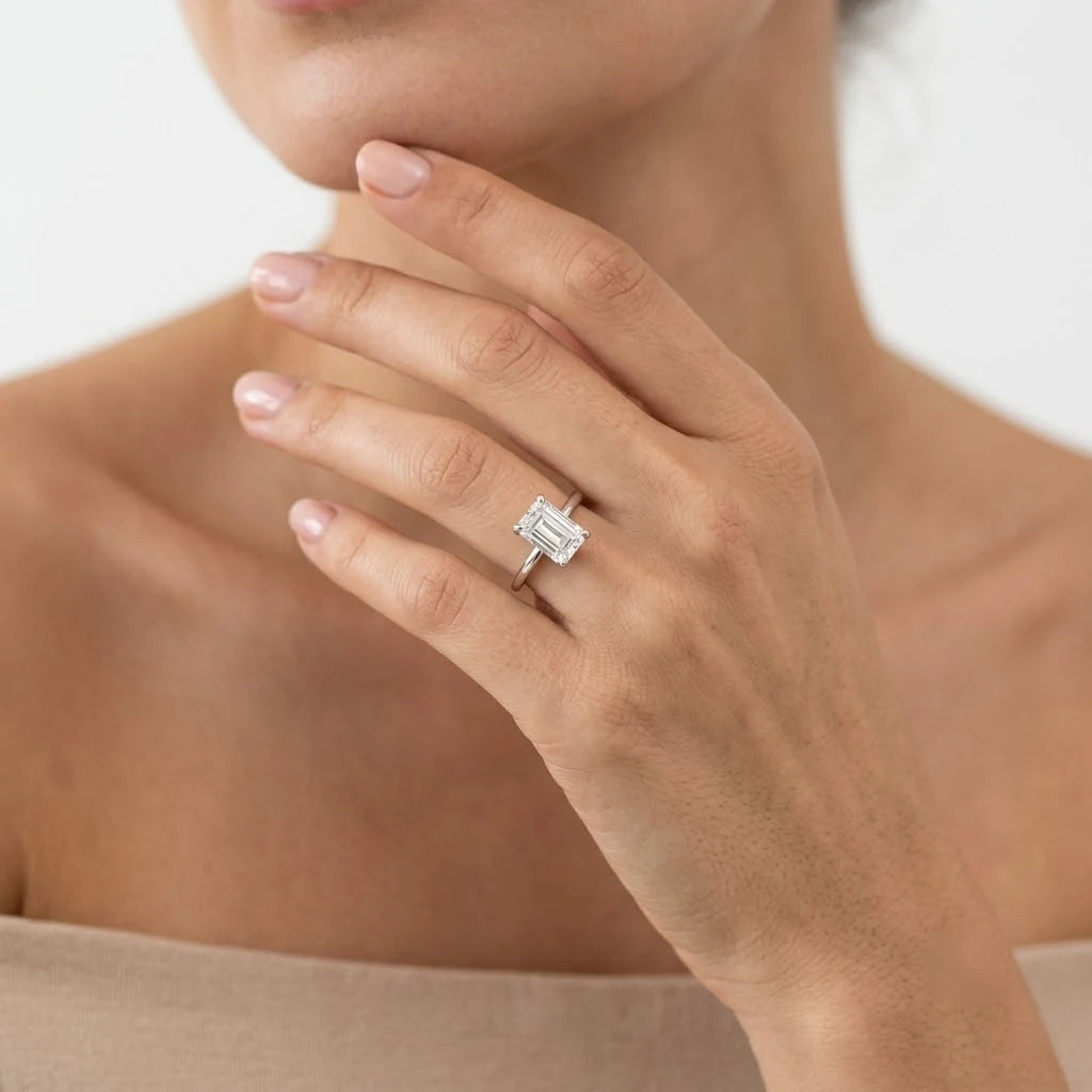 FineDiam emerald cut diamond solitaire engagement ring featuring a rectangular centre stone in a white metal setting.