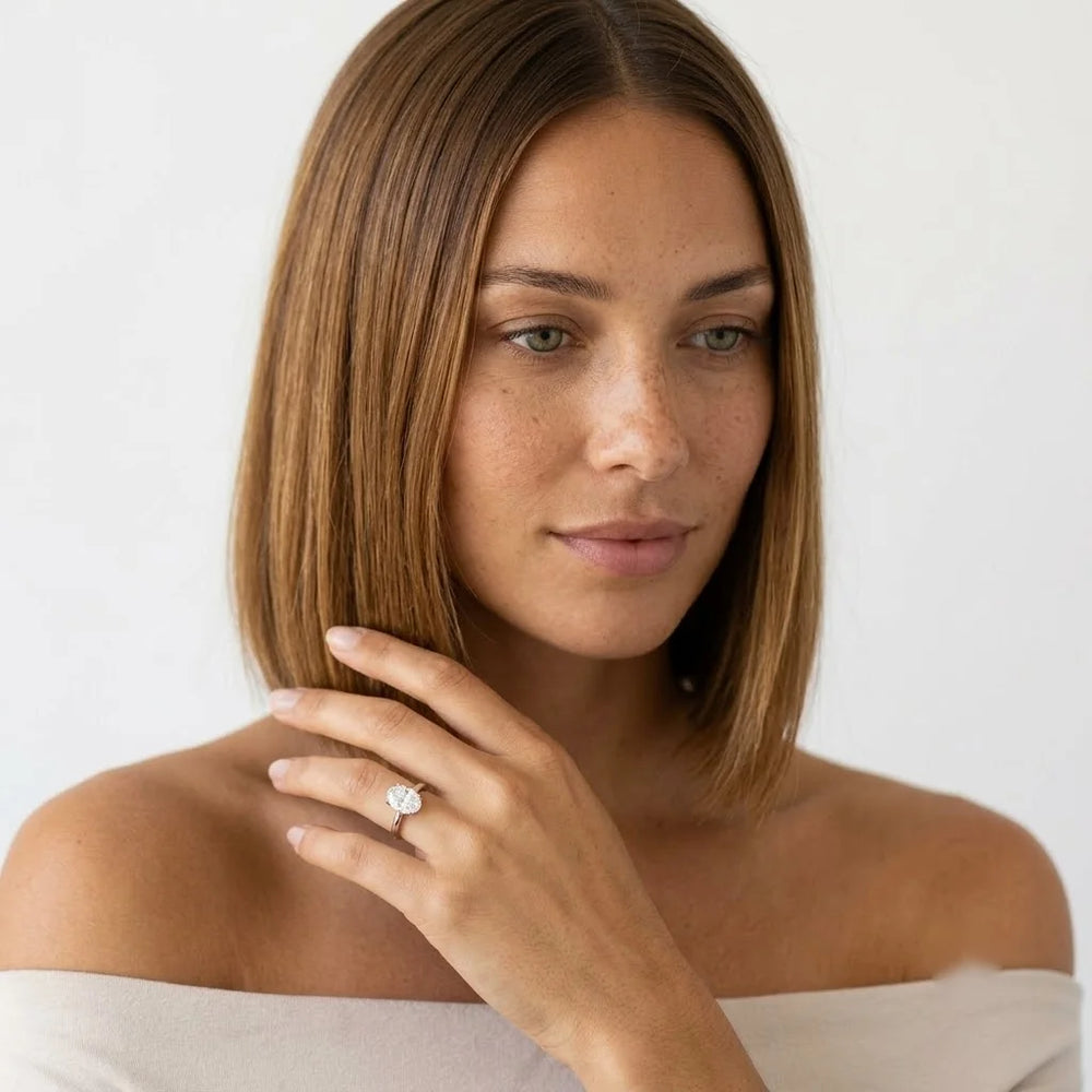  FineDiam oval diamond cluster ring featuring sparkling round stones arranged in an oval setting on a slim white metal band.