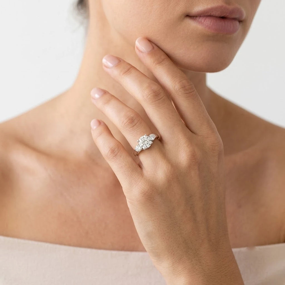 FineDiam pear-shaped diamond cluster ring with smaller round stones and a polished white metal band.