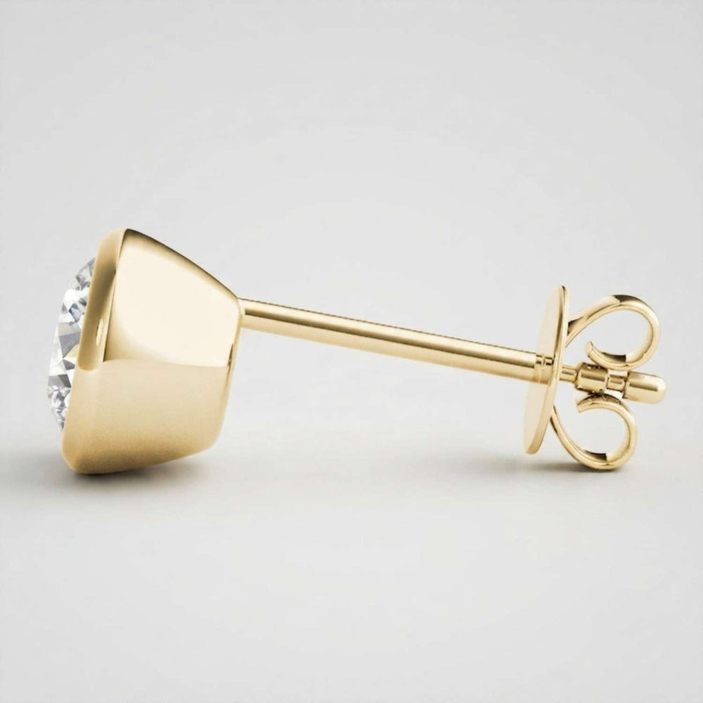 High-end solid gold bezel solitaire studs showcasing a bold, minimalist modern aesthetic.
