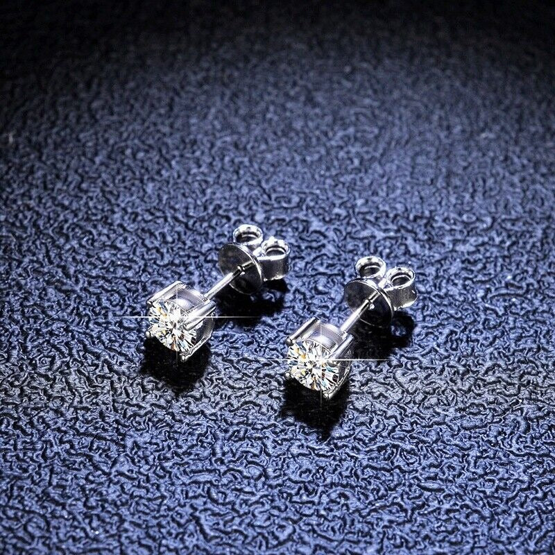 Pair of silver stud earrings with clear gemstones on a textured dark surface