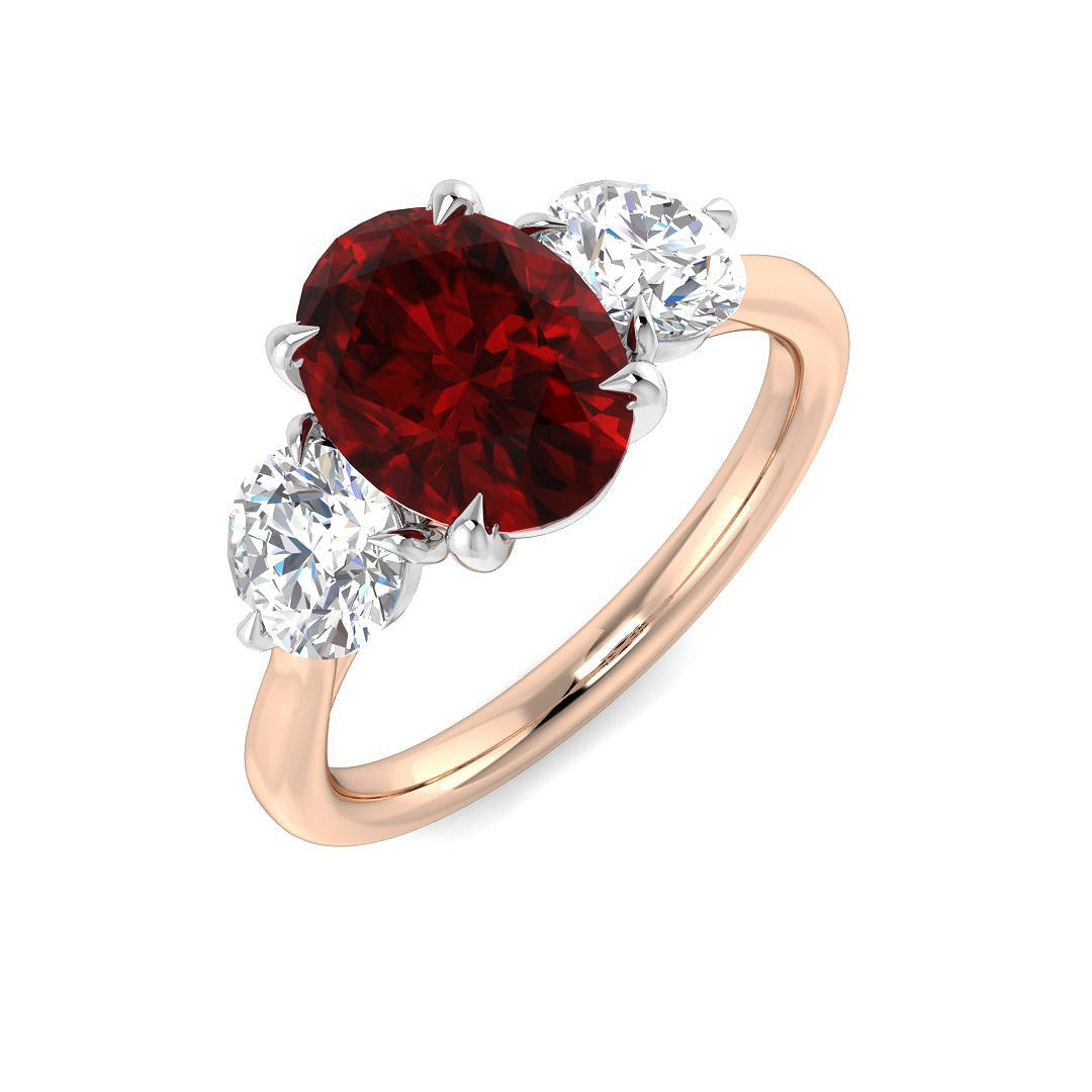 Ruby Three Stone Ring featuring an oval cut ruby center with diamond side stones in a rose gold setting.