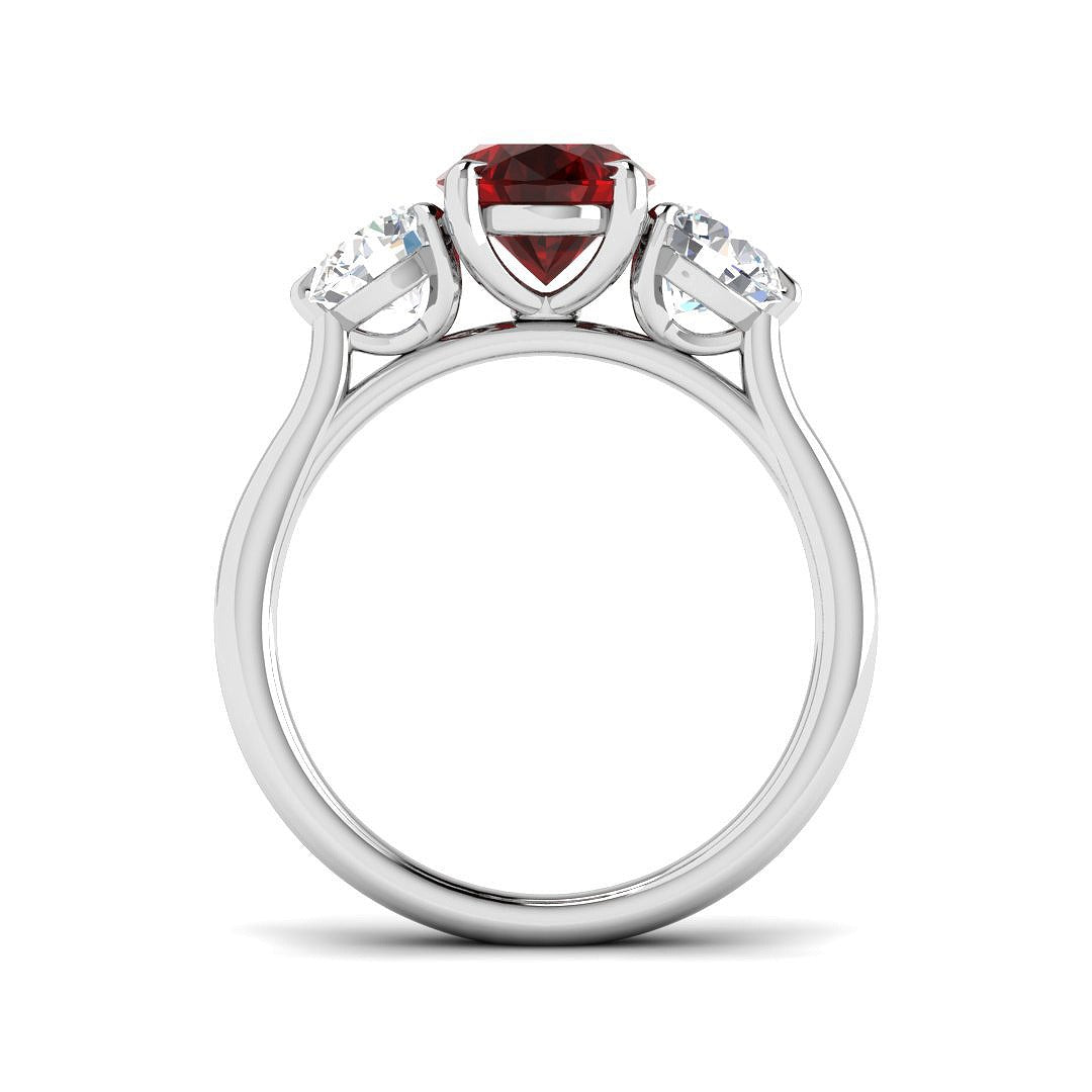 Ruby Three Stone Ring with an oval cut ruby center and sparkling diamond side stones.