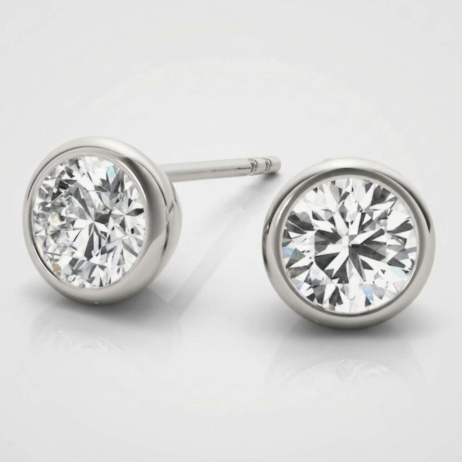 Minimalist solid white gold bezel diamond studs showcasing a sleek rub-over setting.