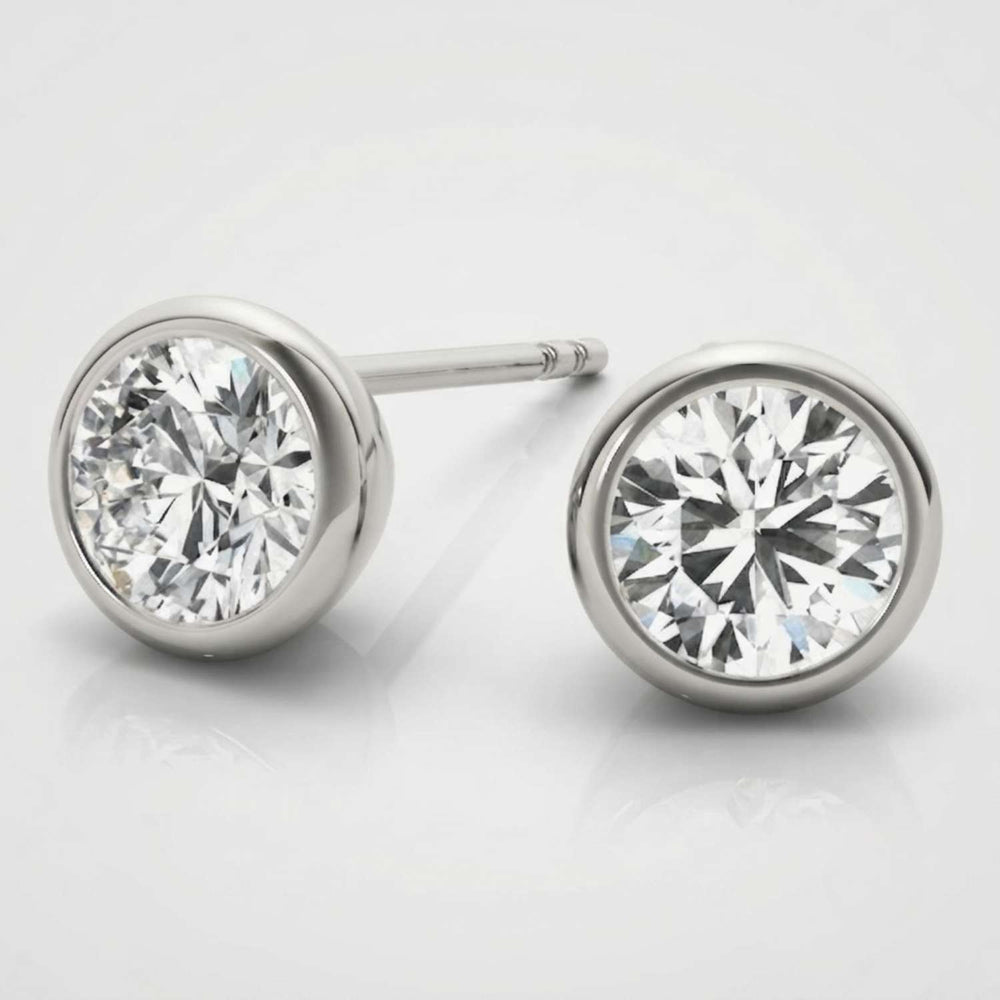 Minimalist solid white gold bezel diamond studs showcasing a sleek rub-over setting.