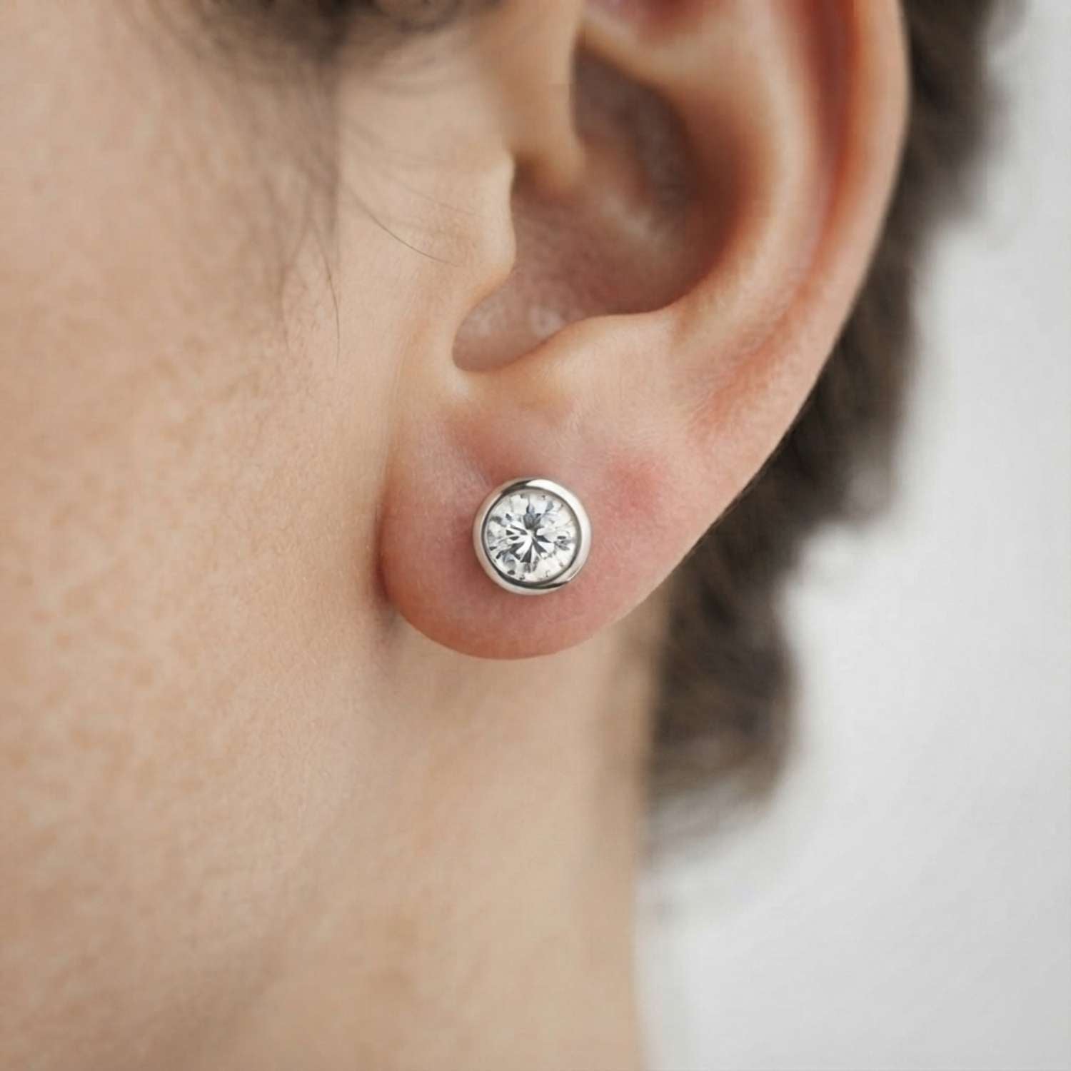 Clean product shot of 18K rose gold bezel-set diamond solitaire earrings against a neutral background.