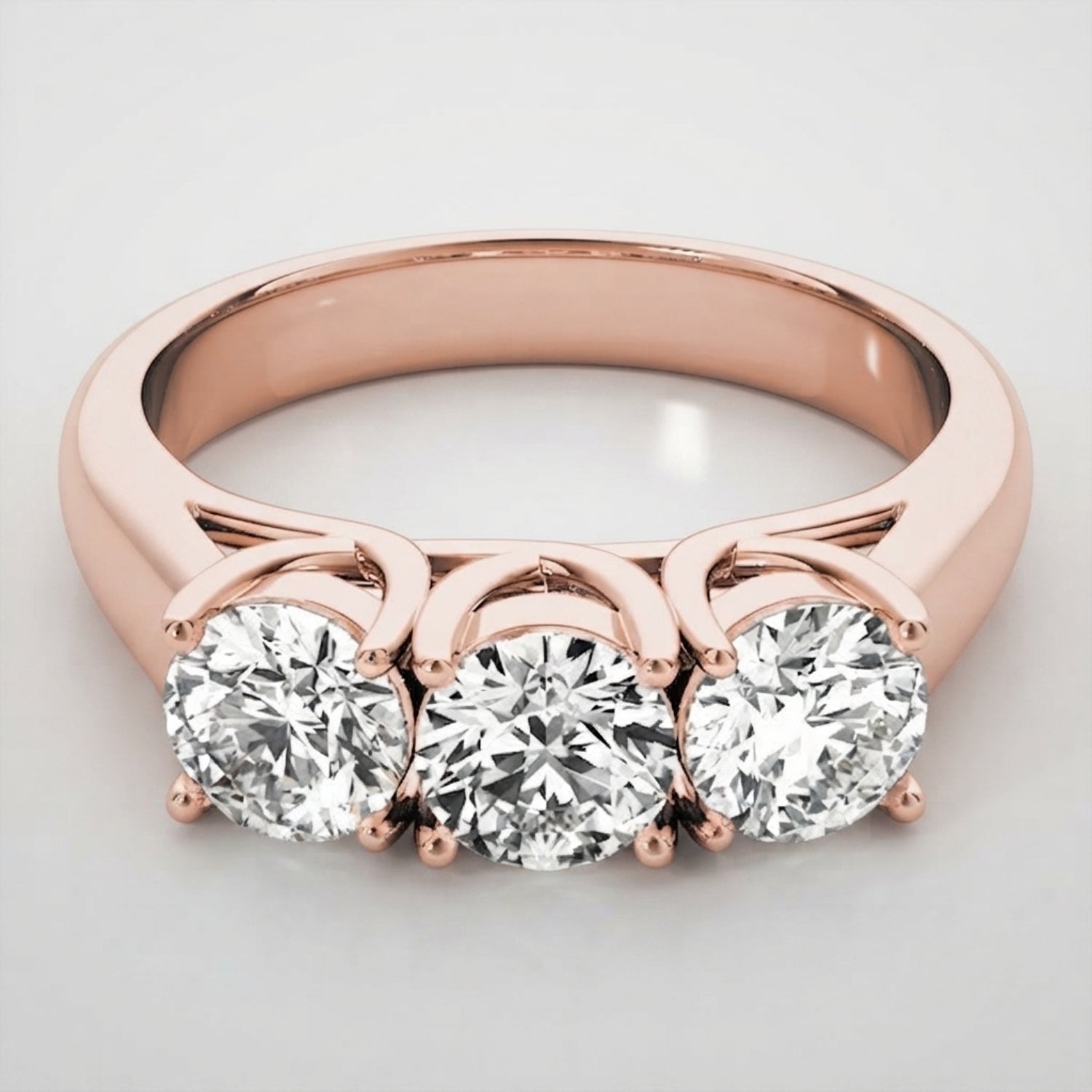 Romantic 18K rose gold round brilliant trilogy engagement ring styled on a clean background.
