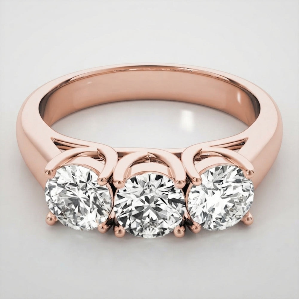 Romantic 18K rose gold round brilliant trilogy engagement ring styled on a clean background.