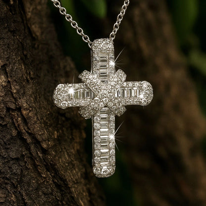 Silver cross pendant with clear stones on a chain against a blurred natural background