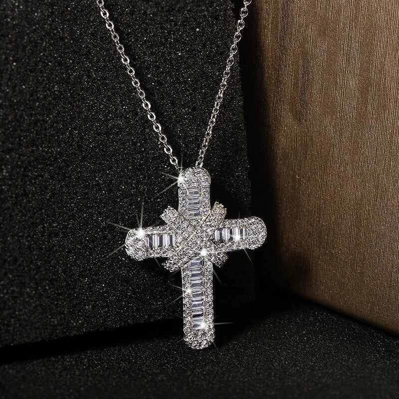 Silver cross necklace with clear stones on a dark background